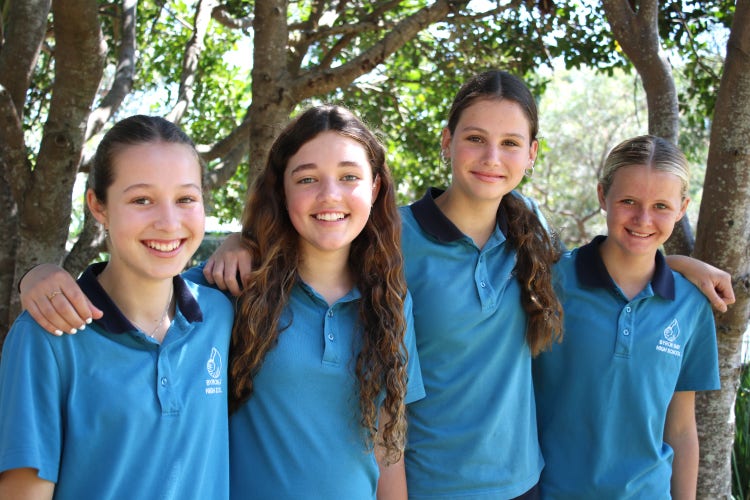 Four students smiling with arms around each other