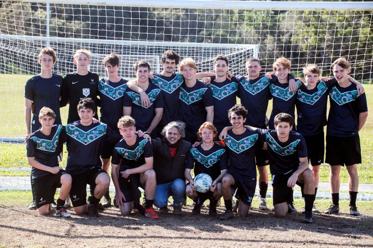 Open Boys soccer team grouped together in front of the soccer goals