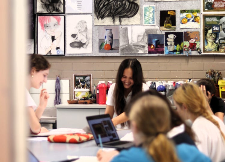 Students smiling as they participate in an art class using computers