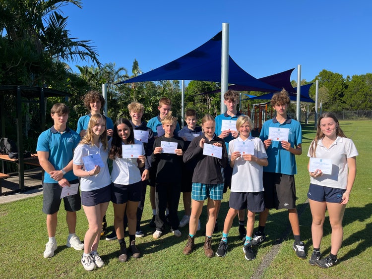 Students posing with certificates they have received at an assemby